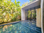 Double-height living space opening to the pool through pivoting glass doors at Casa Aviv, Tulum