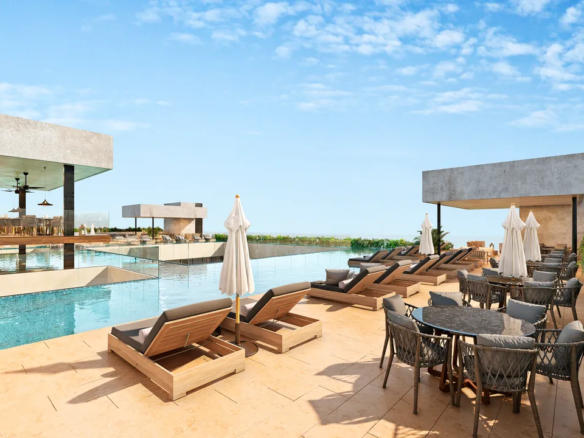 Rooftop infinity pool and bar at Ceiba at 25, overlooking a sports stadium in Playa del Carmen.