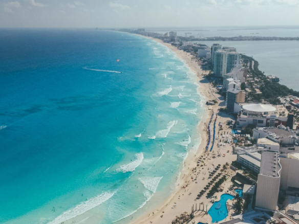 Alt text: "Aerial view of Cancún's Hotel Zone coastline, turquoise Caribbean Sea, beachfront hotels, and Nichupté Lagoon