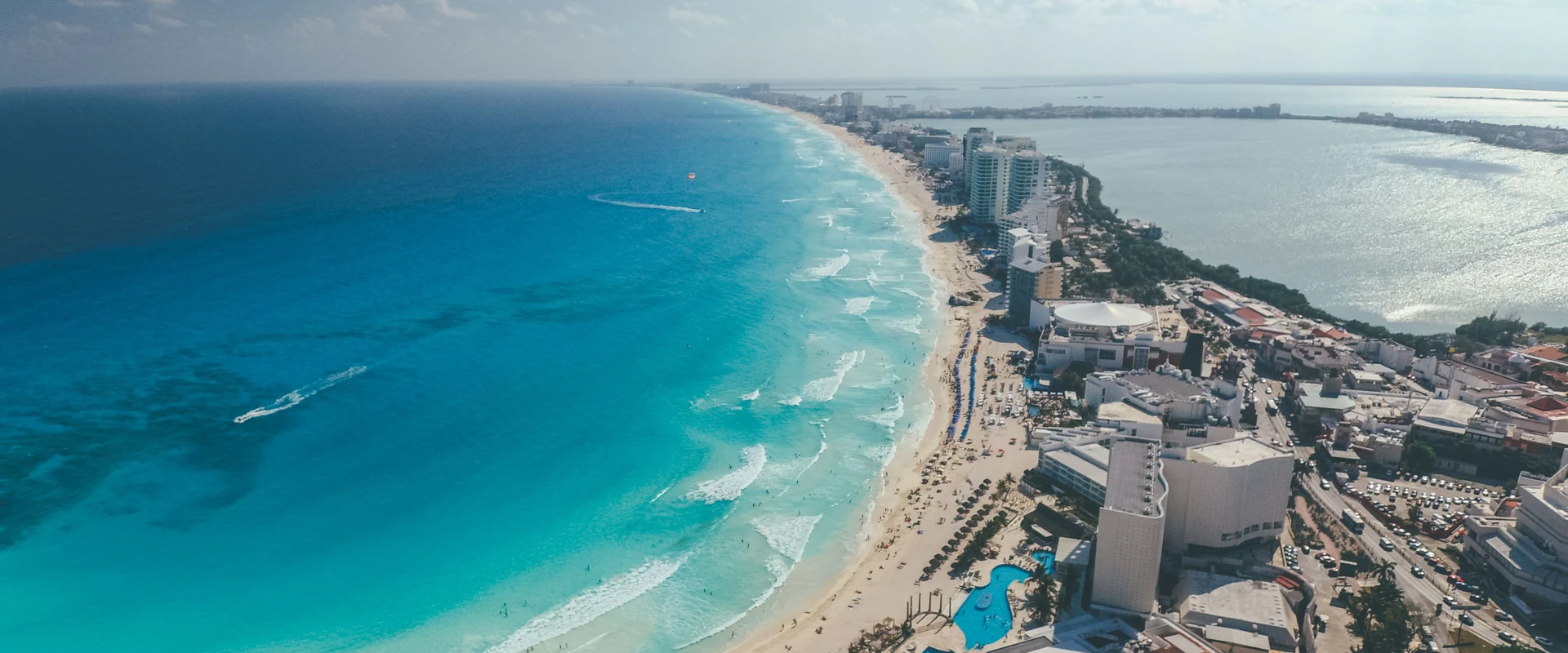 Alt text: "Aerial view of Cancún's Hotel Zone coastline, turquoise Caribbean Sea, beachfront hotels, and Nichupté Lagoon